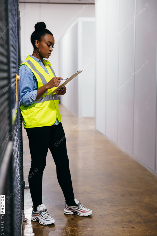 African American woman in datacenter surveying warehouse is secure