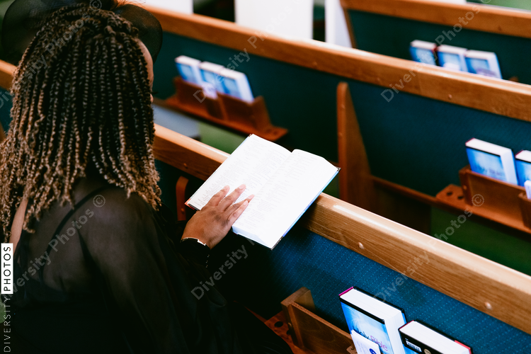 Woman sitting in pews and reading bible at church