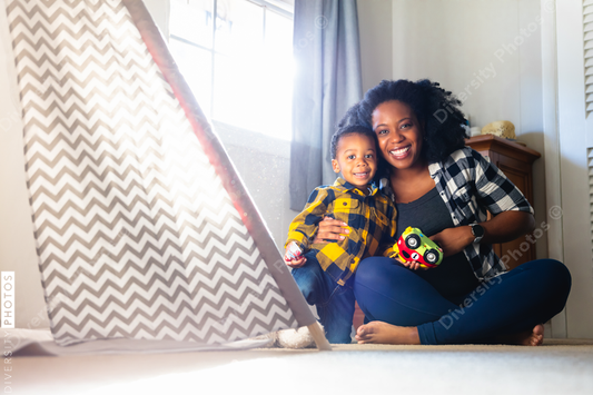 Black mother playing with son at home in nursery