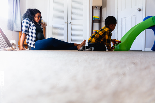 Black mother playing with son at home in nursery