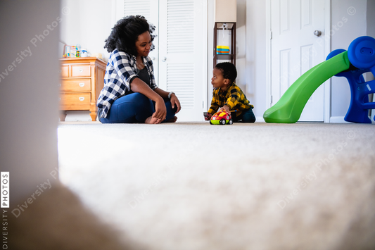 Black mother playing with son at home in nursery