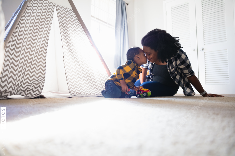 Mother and toddler son having special loving moment at home in play room