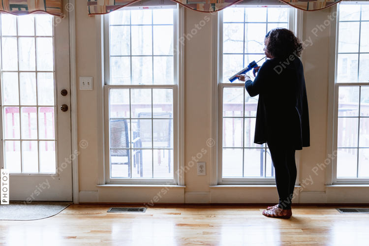 Senior African American woman caulking windows for home energy efficiency