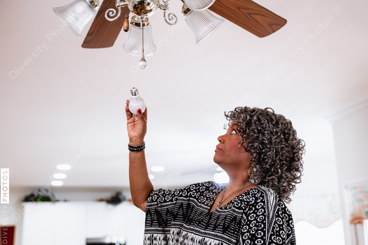 Black senior woman installing energy efficient LED light bults, DIY