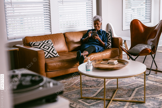 Black senior woman reading news on cellphone at home