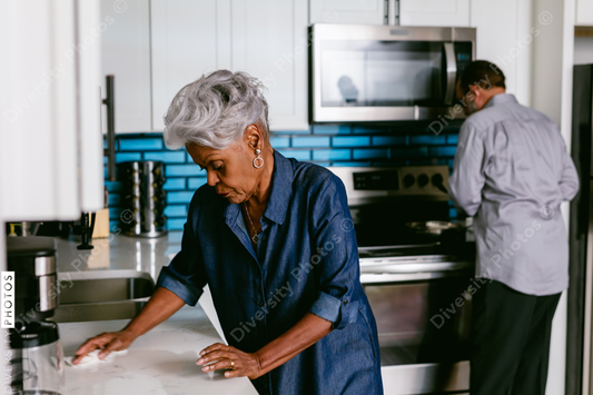 Black senior woman cleaning kitchen at home