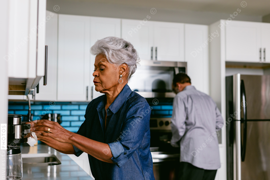 Black senior woman cleaning kitchen at home