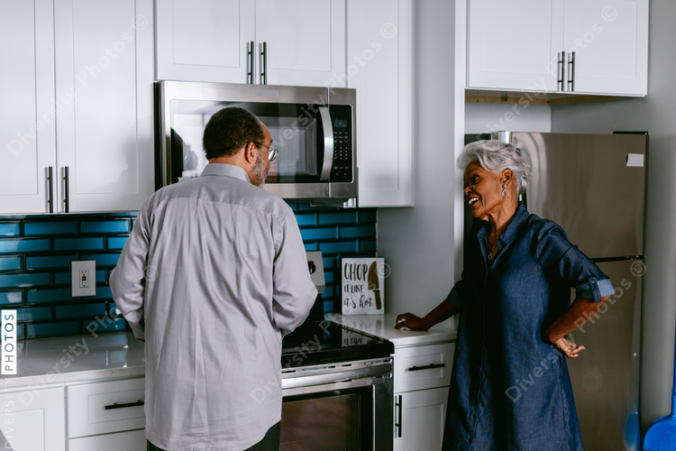 African American husband wife senior couple having conversations in kitchen