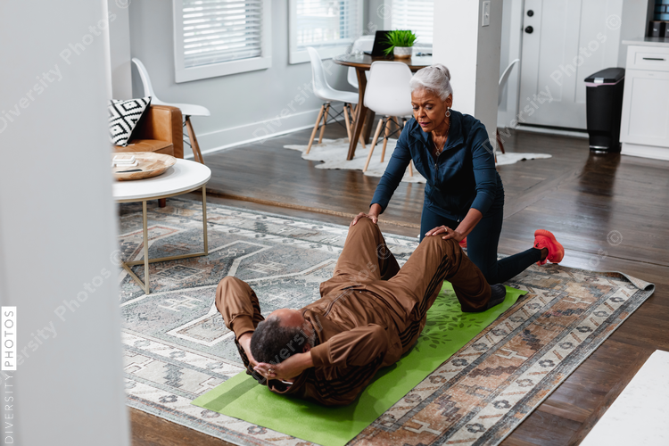 Senior wife helps train husband and exercise in living room