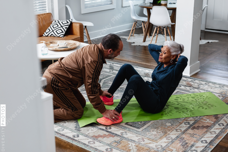 Senior woman doing sit-up exercises with husband, active lifestyle fitness