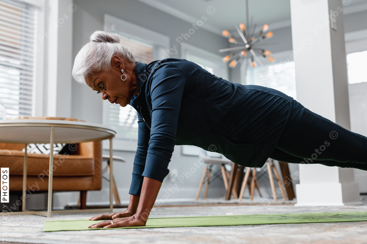 Senior woman working out at home doing planks and pushups