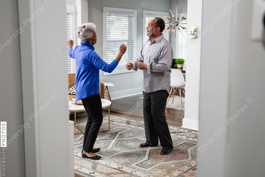 Black senior couple enjoys retirement at home dancing to music