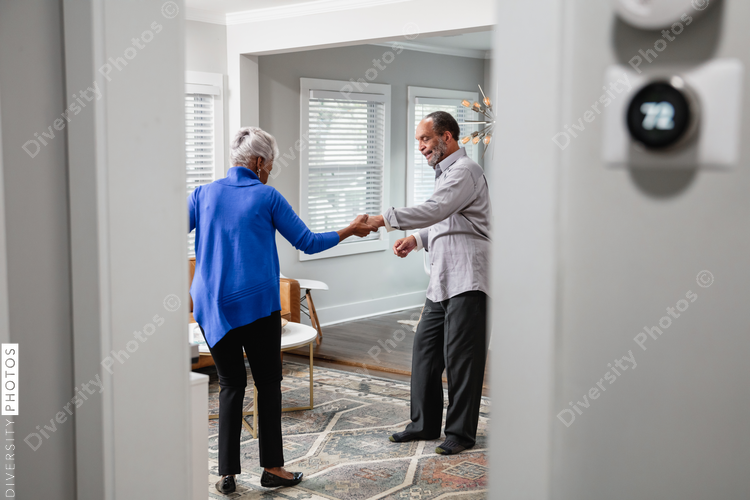 Black senior couple enjoys retirement at home dancing to music