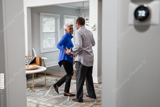Black senior couple enjoys retirement at home dancing to music