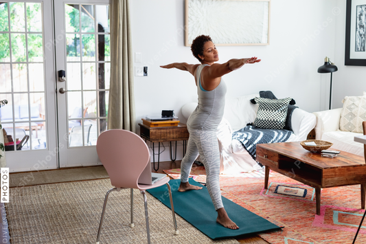 African American woman does yoga watching online tutorial on laptop computer