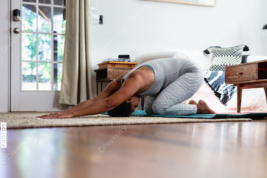 Black woman does downward dog pose in yoga mat