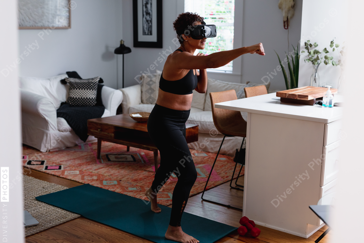 Black woman does boxing exercise at home using virtual reality technology