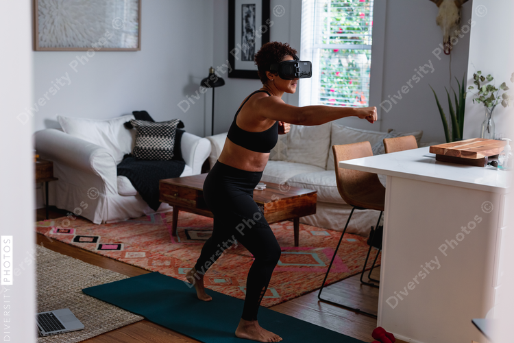 Black woman does boxing exercise at home using virtual reality technology