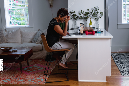 African-American woman works on laptop in home kitchen