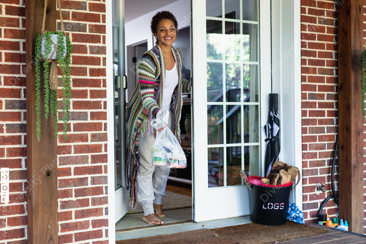 Black woman grabs food delivered to front door at home