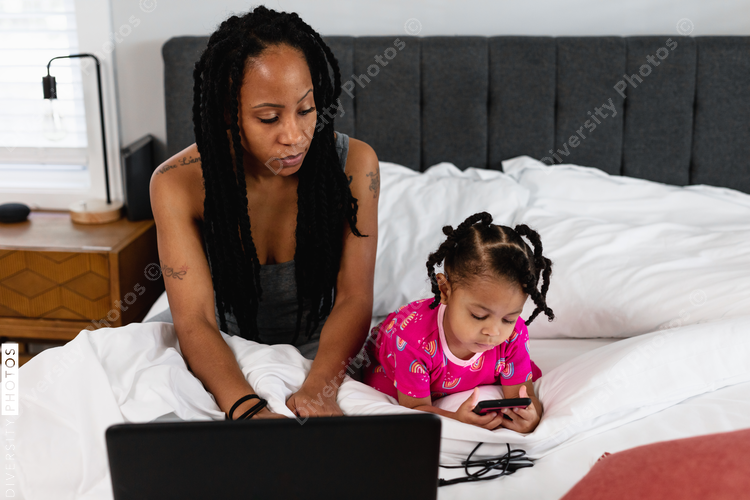 Mom working remotely in bed with child