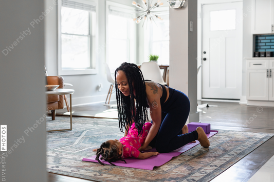 Black mom helps daughter practice yoga exercise together