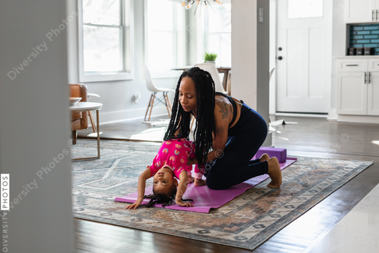 Black mom helps daughter practice yoga exercise together