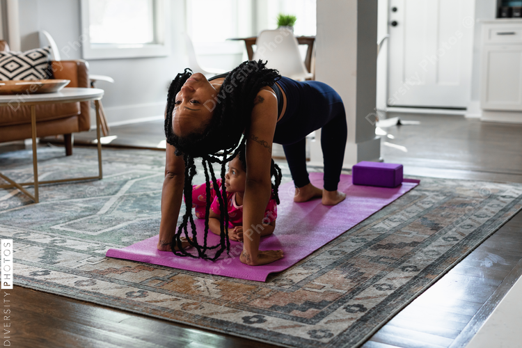Black mother does yoga pose with daughter toddler