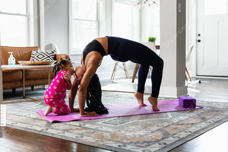 Moment when daughter kiss mother while she does yoga exercise at home