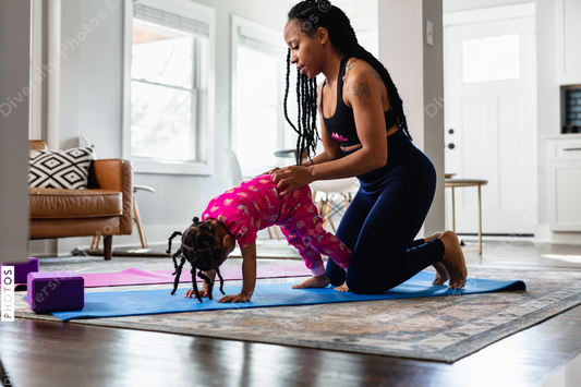 African American mother helping daughter exercise at home