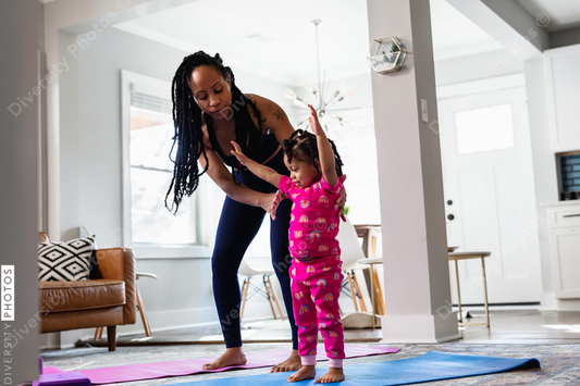 African American mother helping daughter exercise at home