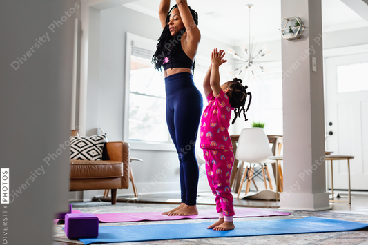 Black Mother and daughter doing yoga in living room