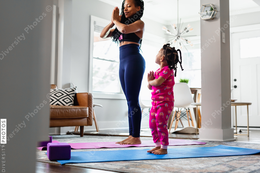 Black Mother and daughter doing yoga in living room