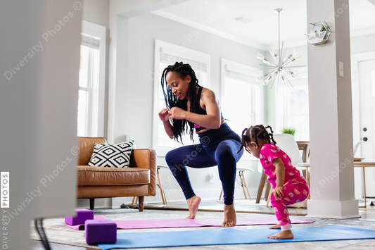 African American Mother and daughter doing yoga in living room