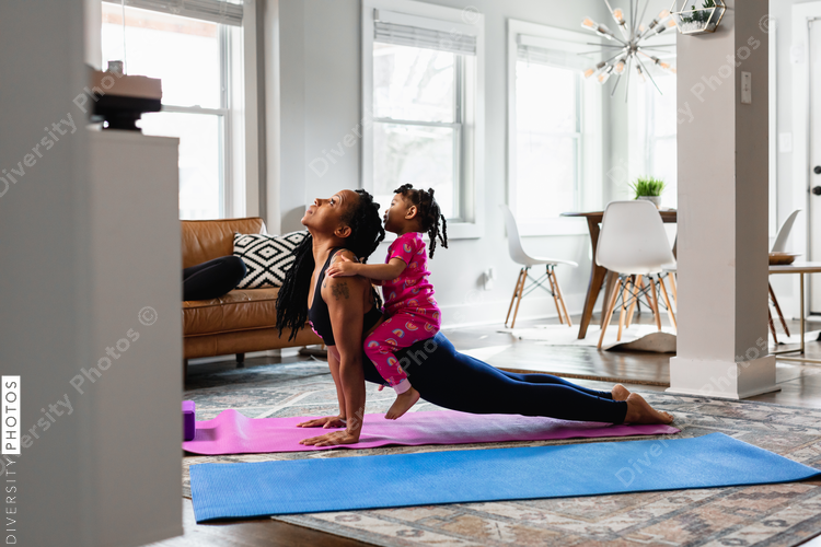 Mother and daughter working out at home doing exercises, yoga upward facing dog