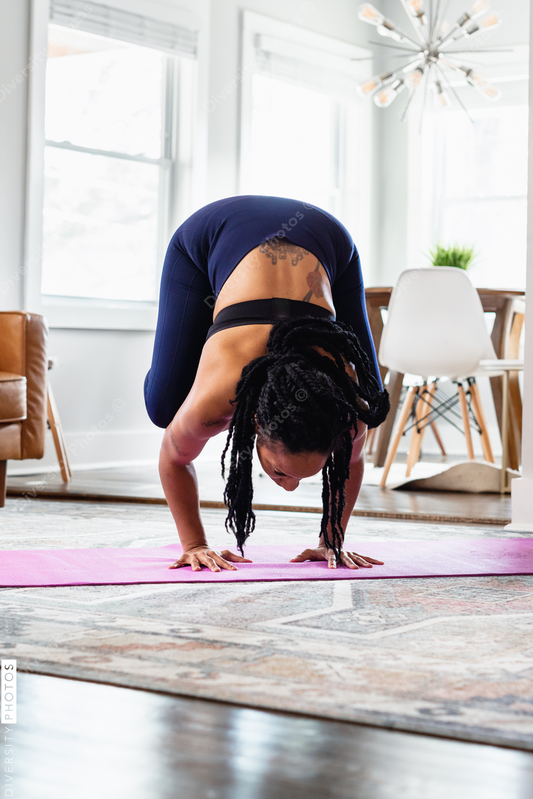 African American woman doing yoga, crane crow, at home in living room