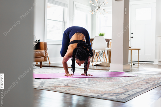 African American woman doing yoga, crane crow, at home in living room