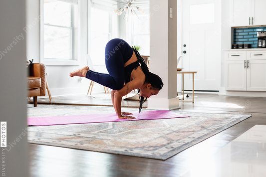 African American woman doing yoga, crane crow, at home in living room