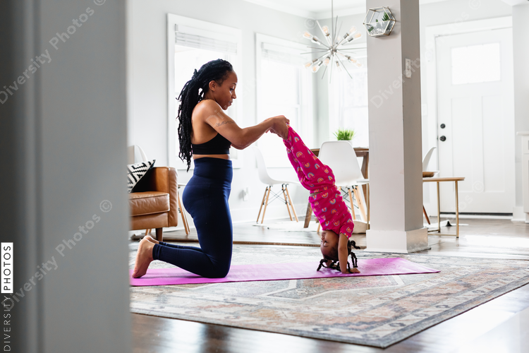 Mother helps daughter do yoga handstand exercise