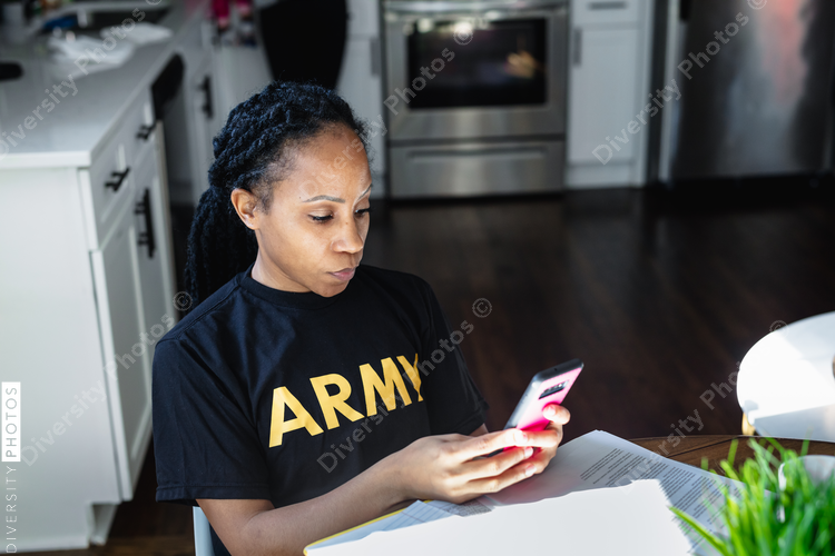 Military woman checking phone at dining room table
