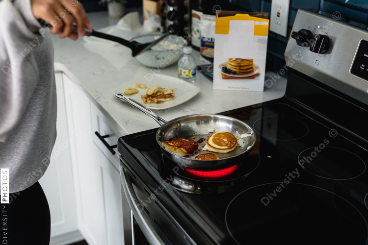 Teen girl cooks breakfast pancakes on stove