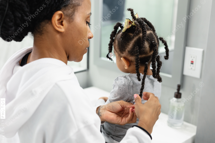 Black woman doing daughters hair at home