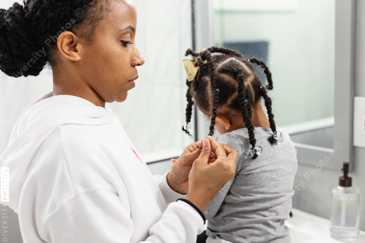 Black woman doing daughters hair at home