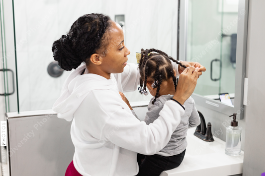 Black woman doing daughters hair at home
