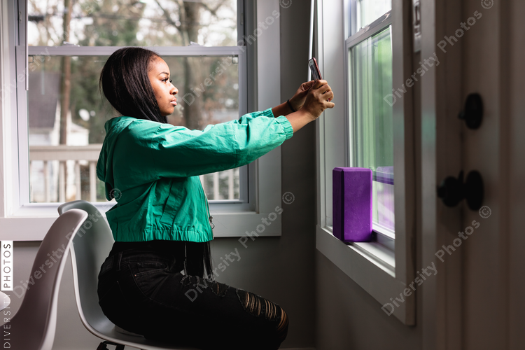 Teen girl taking selfie by window for best light and angle