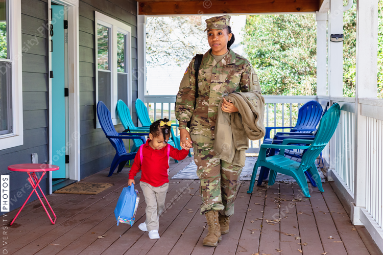 Black woman walking child to school, military personnel