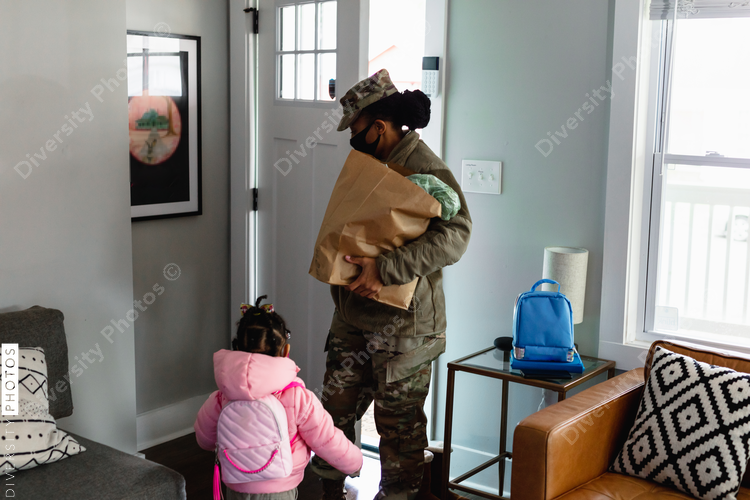 Female mother soldier brings home groceries with daughter