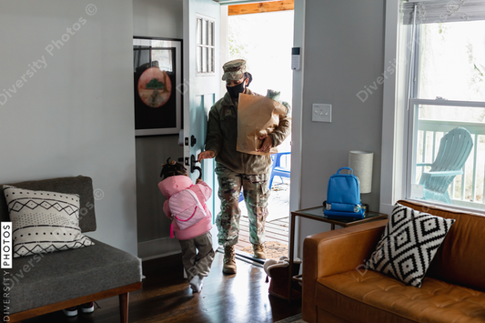 Black soldier brings home groceries with daughter
