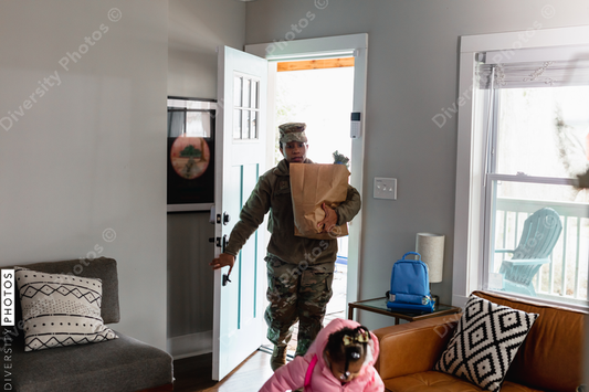 Black soldier brings home groceries with daughter