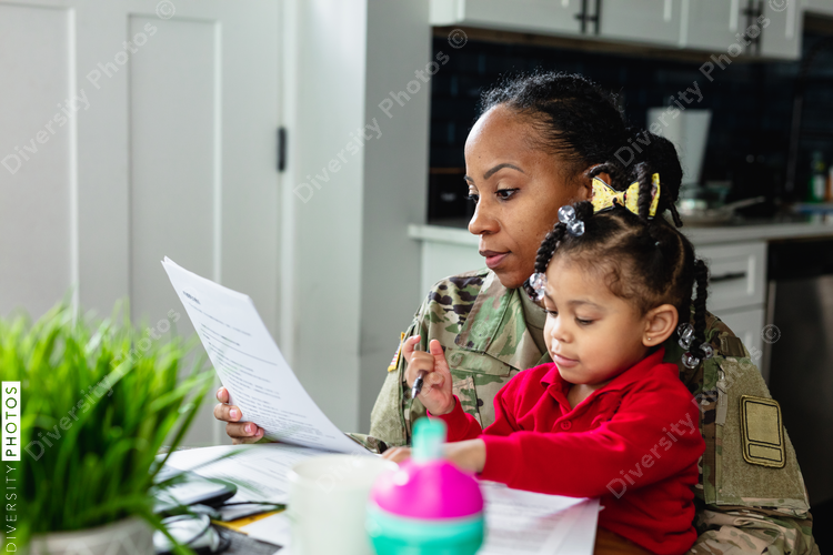 Focused military woman working from home at laptop and paying bills